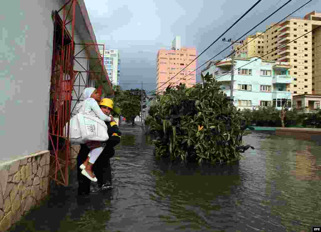  El bombero del destacamento de Rescate y Salvamento Ángel Games carga a una mujer por una calle inundada por las penetraciones del mar hoy, sábado 23 de enero de 2016, en La Habana (Cuba). EFE/Alejandro Ernesto