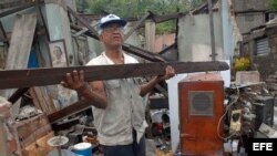  Un hombre rescata algunas pertenencias de su hogar, destruido por el paso del huracán "Sandy" en la ciudad de Santiago de Cuba.