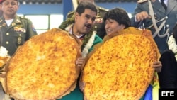 El presidente de Venezuela, Nicolás Maduro (i), y su par boliviano, Evo Morales (d), cargan unos panes gigantescos tradicionales en Cochabamba (Bolivia). 