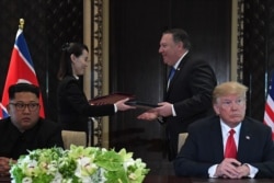 Kim Yo Jong y Michael Pompeo intercambian documentos en la ceremonia de firma de acuerdos de la histórica cumbre de Singapur entre Kim Jong Un y el presidente Donald Trump, el 12 de junio de 2018. (SAUL LOEB / AFP)