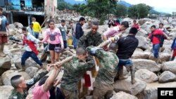 Fotografía cedida por el Ejército de Colombia de sus integrantes ayudando a pobladores por los estragos ocasionados por una avalancha.