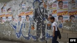 Un niño camina junto a un grafitti en tributo al fallecido presidente venezolano Hugo Chávez en una calle de Caracas (Venezuela).