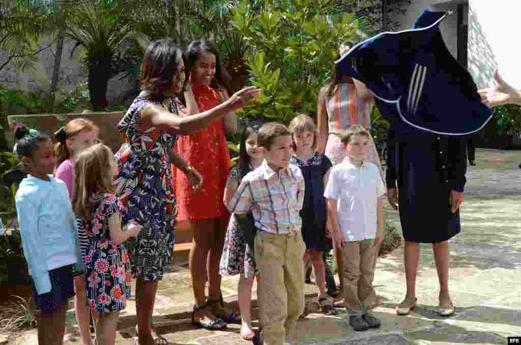 La primera dama estadounidense, Michelle Obama (i), sus hijas Malia (2i) y Sasha (2d) y a su madre, Marian Robinson (d) posan junto a un grupo de niños en una ceremonia en La Habana Vieja.