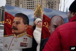 Un partidario del Partido Comunista entre los retratos de los líderes soviéticos Joseph Stalin, izquierda, y Vladimir Lenin en la plaza Manezhnaya en Moscú, Rusia, el jueves 21 de diciembre de 2023. (Foto AP/Alexander Zemlianichenko)