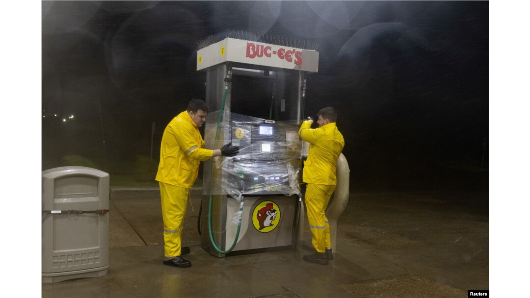 Trabajadores envuelven plástico alrededor de una bomba de combustible para protegerla del viento y la lluvia en Buc-ee's, en Freeport, Texas, el 8 de julio de 2024. REUTERS/Adrees Latif