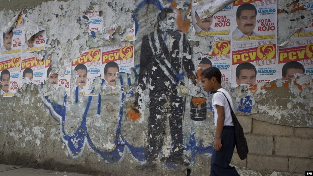 Un niño camina junto a un grafitti en tributo al fallecido presidente venezolano Hugo Chávez en una calle de Caracas (Venezuela).