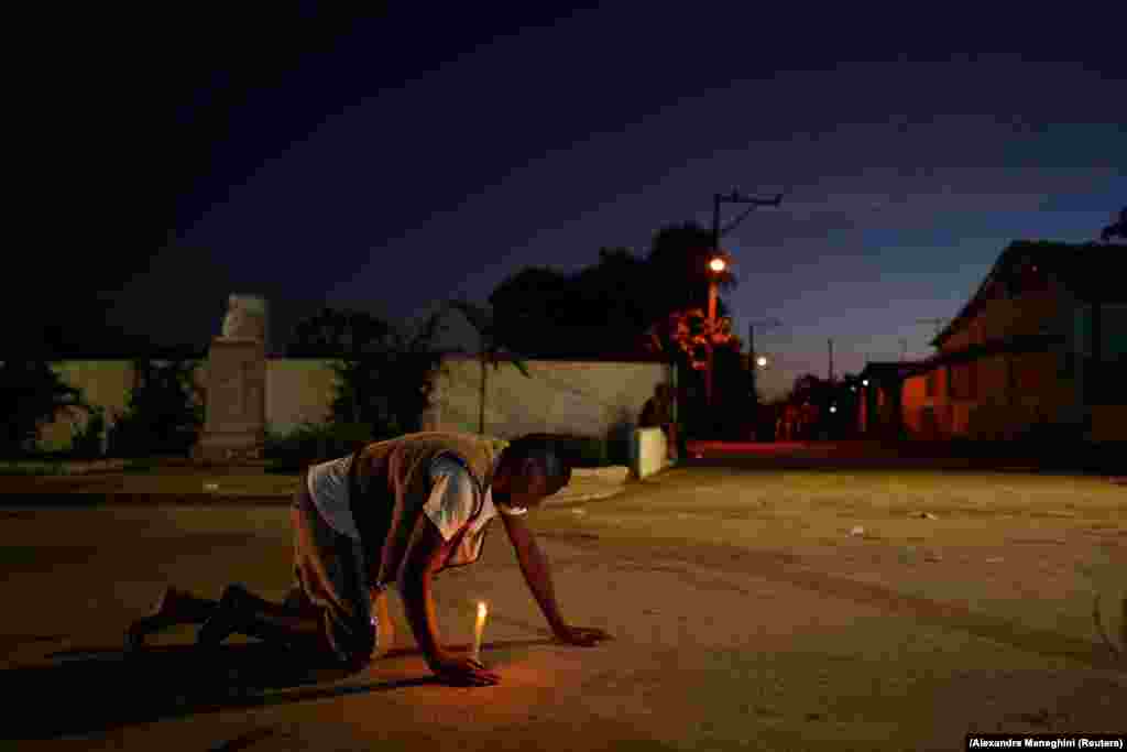 Un peregrino camina de rodillas con una vela encendida camino al Santuario de San Lázaro, en El Rincón, La Habana, este 17 de diciembre. (REUTERS/Alexandre Meneghini)