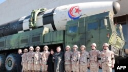 Kim Jong Un (centro a la derecha) y su hija (centro a la izquierda) posando con soldados que contribuyeron a la prueba de fuego del nuevo misil balístico intercontinental. (Foto: KCNA VIA KNS / AFP)