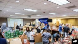 Empleados de Ryder, una empresa de logística de camiones y suministros de Miami, hacen trabajo voluntario para su campaña anual de recaudación de fondos para la organización benéfica “United Way”. (© Business Wire/AP Images)
