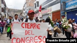 Un hombre camina con un cartel con un mensaje en español que dice "Cierre del Congreso", en el cortejo fúnebre de Clemer Rojas, de 23 años, que murió en las protestas, en Ayacucho, Perú. (AP Foto/Franklin Briceño)