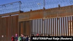 Migrantes de Nicaragua, Ecuador y otras nacionalidades en una puerta en el muro fronterizo esperando ser recogidos por la Patrulla Fronteriza de Estados Unidos en El Paso, Texas, EE. UU., 4 de enero de 2023. REUTERS/Paul Ratje