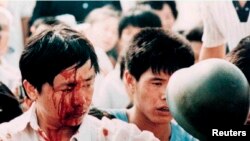 Un manifestante herido sostiene el casco de un militar en la Plaza de Tiananmén el 4 de junio de 1989 (Archivo/Shunsuke Akatsuka/Reuters).