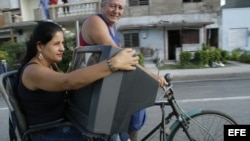 Una mujer transporta un televisor en un "bicitaxi".