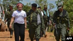 El comandante guerrillero de las Fuerzas Armadas Revolucionarias de Colombia (FARC), Jairo (C), camina junto a Piedad Córdoba (L) en San Isidro, Caquetá, el 30 de mayo de 2012. Luis ACOSTA/AFP