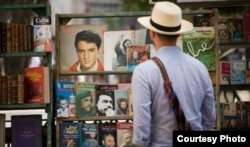 Un turista revisa viejos libros revolucionarios ofrecidos por un cuentapropista.