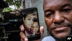 Emilio Román muestra una foto de su hijo Yosney y su hija Mackyanis, quienes fueron condenados a 10 años por cargos de sedición por participar en las protestas del 11J en La Güinera, La Habana. Imagen del 1 de julio de 2022. (Foto AP/Ramón Espinosa).
