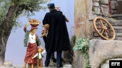 Un miembro de la gendarmería vaticana cubre y detiene a una activista de Femen que intentó llevarse la figura del niño Jesús del belén instalado en la Plaza de San Pedro del Vaticano.