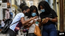 Cubanas usando el celular en las calles de La Habana. (Photo by YAMIL LAGE / AFP).