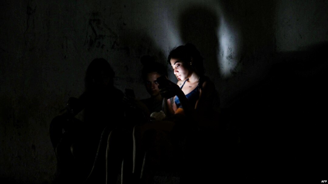 Cubanos usan sus teléfonos para alumbrarse en la oscuridad del apagón, el 18 de marzo, un día después de las protestas populares en varias localidades del país. (Yamil Lage/AFP)