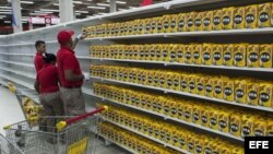 Trabajadores de un supermercado perteneciente a la red pública de alimentación del Gobierno reponen los productos en una estantería.