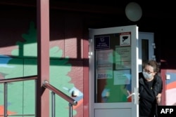 Una empleada con mascarilla vigila la entrada de un hospital de enfermedades infecciosas en Shelejov, Irkutsk.