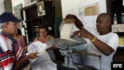 Bodeguero despacha el arroz por la libreta de racionamiento en una bodega de La Habana.