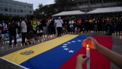 Una mujer sostiene una vela durante una vigilia por las familias afectadas por los terremotos del 24 de junio en la Universidad Central de Venezuela, en Caracas.