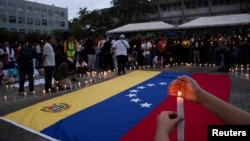 Una mujer sostiene una vela durante una vigilia por las familias afectadas por los terremotos del 24 de junio en la Universidad Central de Venezuela, en Caracas.