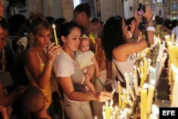 Un grupo de fieles cubanos prende velas dentro de la Iglesia.