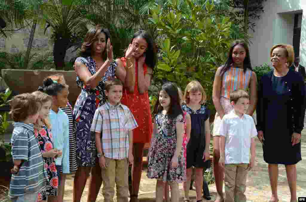 La primera dama estadounidense, Michelle Obama (i), sus hijas Malia (2i) y Sasha (2d) y a su madre, Marian Robinson (d) posan junto a un grupo de niños en una ceremonia en La Habana Vieja.