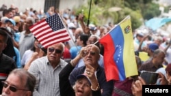 Una miembro del partido de oposición "Vente Venezuela" sostiene las banderas de Estados Unidos y Venezuela mientras participa en la reapertura de la sede del partido, en Caracas el 28 de marzo de 2026. REUTERS/Leonardo Fernandez Viloria