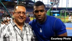 El periodista Edemio Navas (i) junto al jardinero derecho de los Dodgers de Los Ángeles, Yasiel Puig (d).