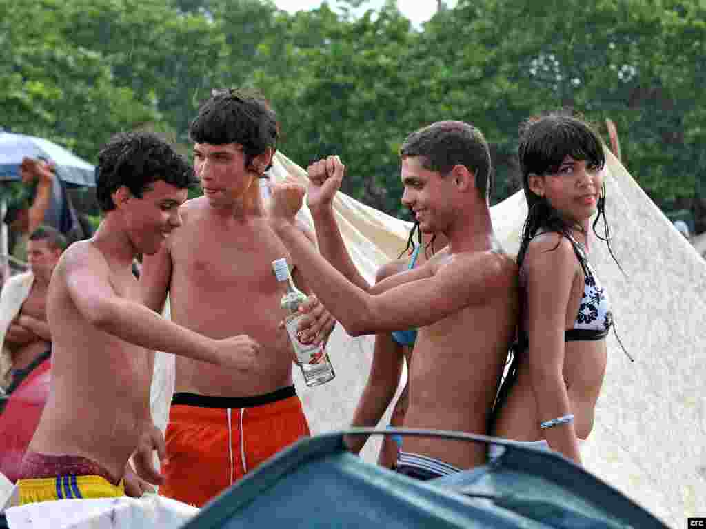 Jóvenes toman bebidas alcohólicas en la playa