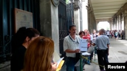 Un trabajador pide un documento necesario a la gente que hace cola en la embajada de España en La Habana el 16 de octubre de 2012. (REUTERS)