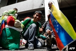 Migrantes venezolanos esperan frente a la embajadade su país en Quito para regresar a Venezuela.