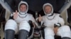 Los astronautas Robert Behnken (izq.) y Douglas Hurley saludan a su regreso a la Tierra dentro de la cápsula SpaceX Dragon.