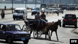 HAB04. LA HABANA (CUBA), 20/08/12 .- Dos hombres transitan en un coche hoy, lunes 20 de agosto de 2012, en La Habana (Cuba). El Estado cubano autorizó la creación de la primera sección sindical de cocheros, conductores de carros tirados por caballos, form