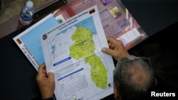 Un miembro de la Asamblea Nacional de Venezuela sostiene un mapa de la diputada región del Esequibo, en Guyana. (REUTERS/Leonardo Fernandez Viloria)