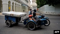 Una familia transporta un colchón en una motocicleta por las calles de La Habana. 