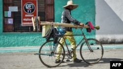 Un hombre camina con su bicicleta de la mano por una calle de Santa Clara. 