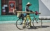 Un hombre camina con su bicicleta de la mano por una calle de Santa Clara.