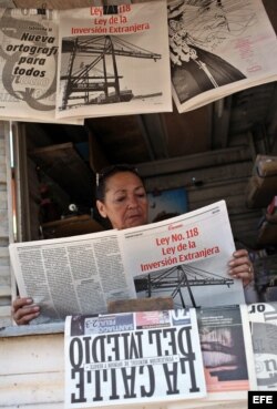 Una vendedora de periódicos lee un tabloide especial confeccionado por el diario Granma donde se divulga la nueva Ley de Inversión Extranjera.