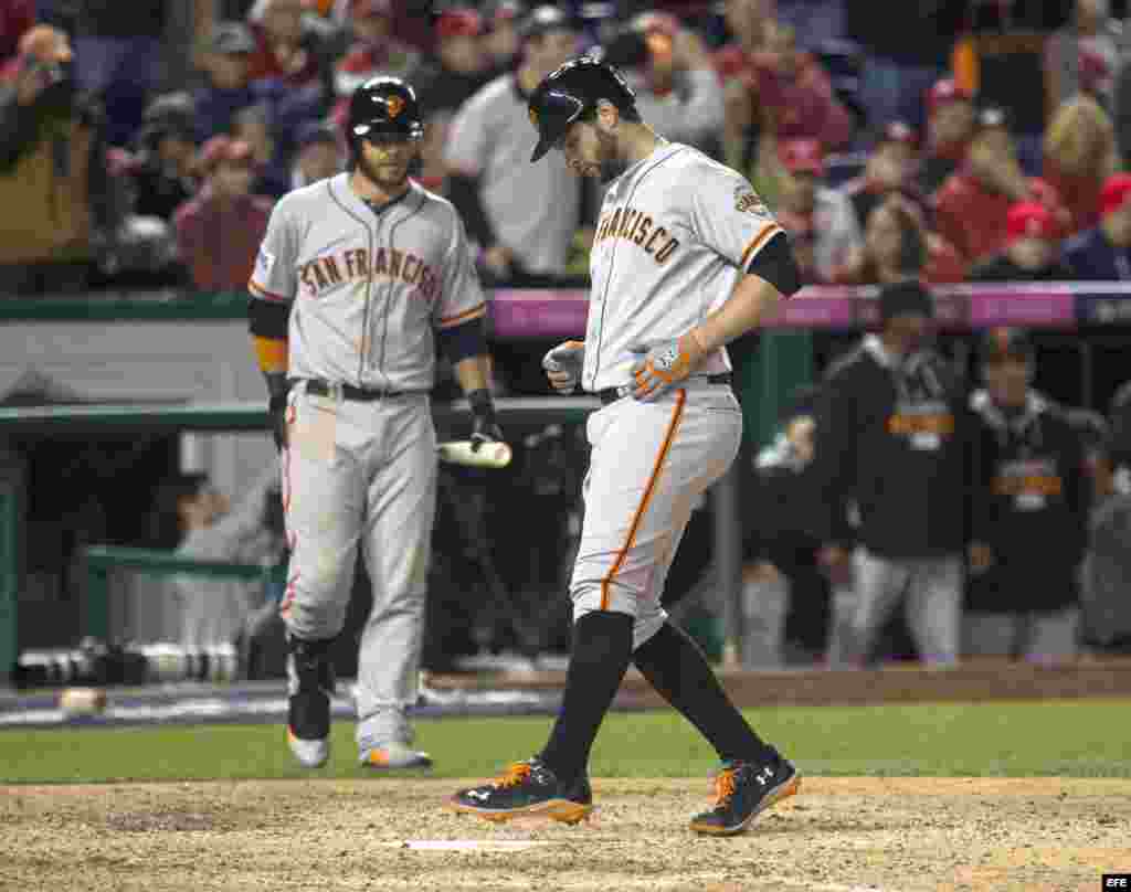 Brandon Belt (d) de los Gigantes de San Francisco llega al plato para anotar la carrera del triunfo en la 18 entrada. 