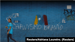 Una mujer pasa frente a un graffiti de la campaña de Nicolás Maduro