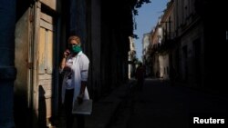 Una doctora espera en a entrada de una vivienda para chequear posibles casos de COVID-19. REUTERS/Alexandre Meneghini
