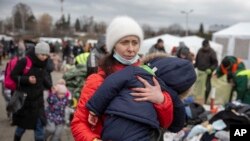 Una mujer que huyó de Ucrania carga a su hijo a su llegada al cruce fronterizo de Medyka, el lunes 28 de febrero de 2022, en Polonia. (AP Foto/Visar Kryeziu)