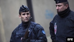 Agentes de policía franceses permanecen en guardia en una calle junto a la sede del semanario satírico francés "Charlie Hebdo".