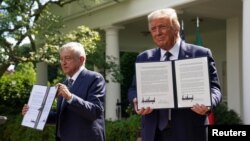 Los presidentes de Estados Unidos y México, Donald Trump y Andrés Manuel López Obrador, muestran sendas copias de la declaración conjunta firmada por ambos minutos antes en los jardines de la Casa Blanca (Kevin Lamarque/Reuters).