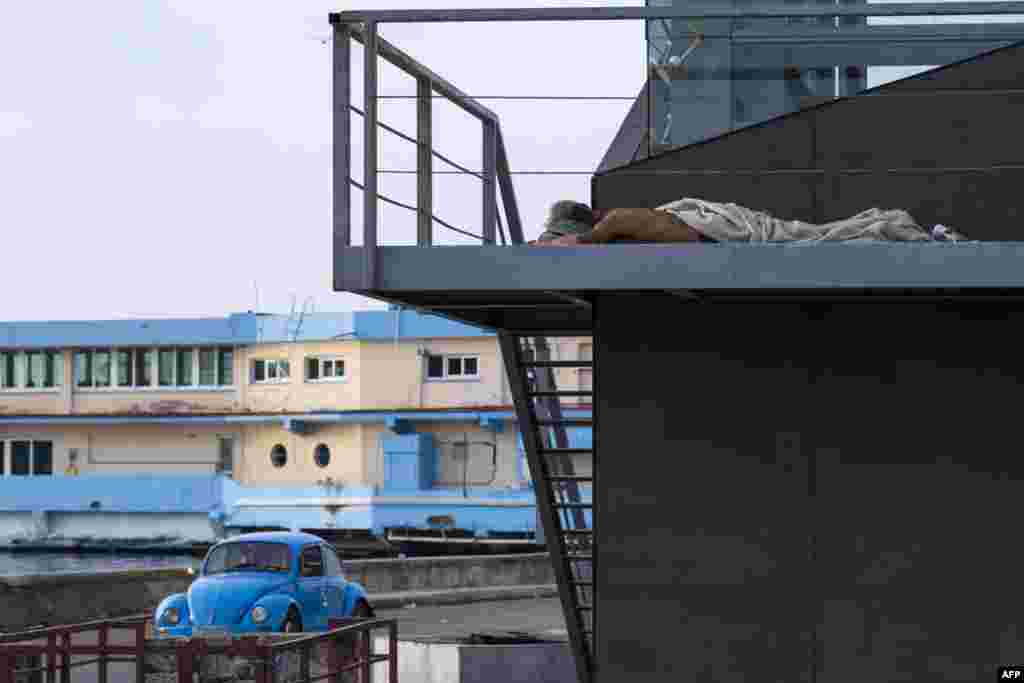 Un hombre duerme envuelto en una sábana en una calle de La Habana el 14 de agosto de 2026. YAMIL LAGE / AFP.
