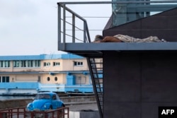Un hombre duerme envuelto en una sábana en una calle de La Habana el 14 de agosto de 2026. Muchos cubanos duermen al aire libre durante las noches de verano en busca de alivio ante las altas temperaturas y los frecuentes cortes de electricidad. (Foto de YAMIL LAGE / AFP)